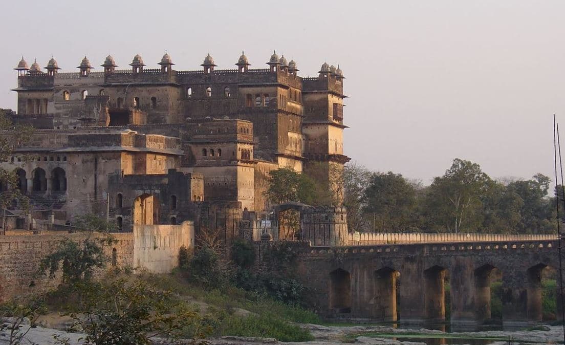 Orchha Fort rising above the bridge and river
